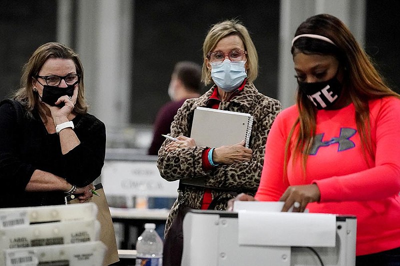 Observers watch an official work Wednesday at the Georgia World Congress Center in Atlanta as ballots are counted in Georgia’s Senate runoff elections. Turnout exceeded both sides’ expectations.
(AP/Brynn Anderson)