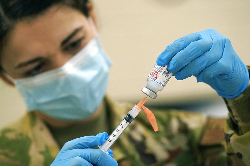 Capt. Brandy Lee with the Mississippi Air National Guard withdraws a dose of the Moderna covid-19 vaccine in Flowood, Miss., in this Dec. 23, 2020, file photo. The dose was about to be injected into the arm of a Mississippi Air or Army National Guard service member who serves as a first responder.