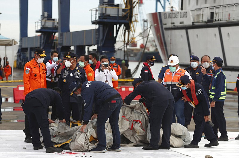 Rescuers inspect debris at the search and rescue command center at Tanjung Priok Port in Jakarta, Indonesia, early Sunday, Jan. 10, 2021, local time. The debris was found in the waters around the location where a Sriwijaya Air passenger jet lost contact with air traffic controllers shortly after takeoff from Jakarta hours earlier.