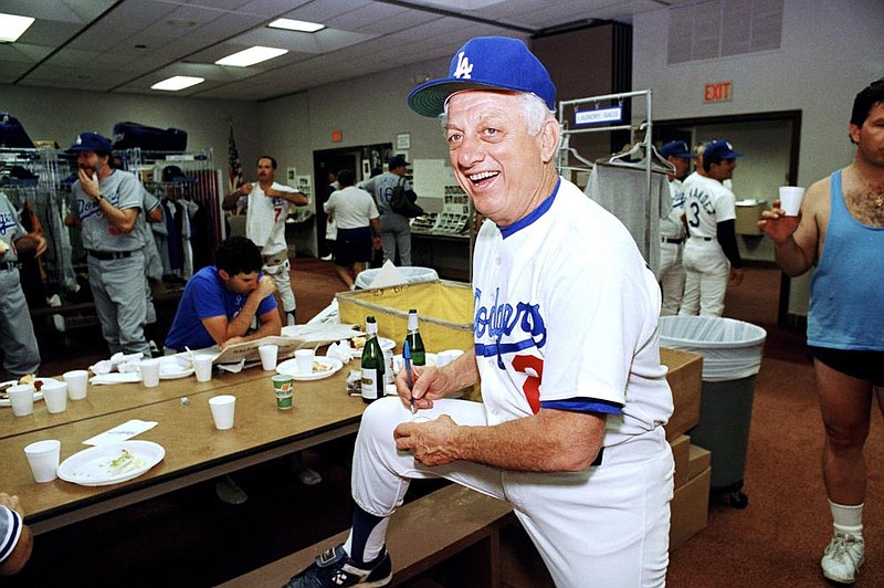  Los Angeles Dodgers manager Tommy Lasorda autographs a baseball in the Dodgertown locker-room in Vero Beach, Fla., in this Wednesday, Feb. 15, 1990, file photo. Tommy Lasorda, the fiery Hall of Fame manager who guided the Los Angeles Dodgers to two World Series titles and later became an ambassador for the sport he loved during his 71 years with the franchise, has died. 
 (AP Photo/Richard Drew, File)