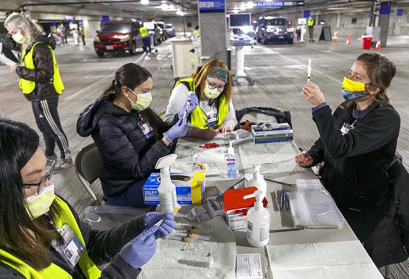 FILE - In this Sunday, Jan. 10, 2021, file photo, Medical professionals from Oregon Health & Science University load syringes with the Moderna covid-19 vaccine at a drive-thru vaccination clinic in Portland, Ore. The U.S. is entering the second month of the largest vaccination effort in history with a massive expansion of the campaign, opening up football stadiums, major league ballparks, fairgrounds and convention centers to inoculate a larger and more diverse pool of people. (Kristyna Wentz-Graff/Pool Photo via AP, File) story.lead_photo.caption