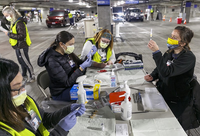 FILE - In this Sunday, Jan. 10, 2021, file photo, Medical professionals from Oregon Health & Science University load syringes with the Moderna COVID-19 vaccine at a drive-thru vaccination clinic in Portland, Ore. The U.S. is entering the second month of the largest vaccination effort in history with a massive expansion of the campaign, opening up football stadiums, major league ballparks, fairgrounds and convention centers to inoculate a larger and more diverse pool of people.