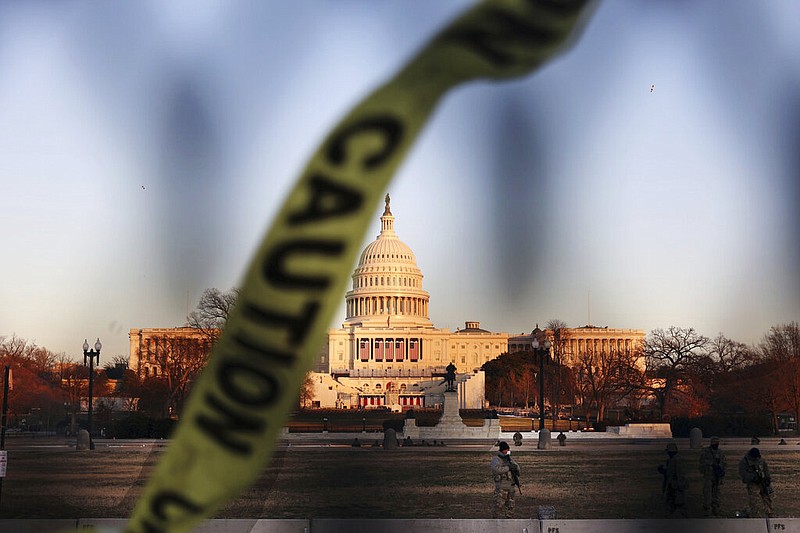 Caution tape flies Wednesday, Jan. 13, 2021, on a fence that was erected to reinforce security at the Capitol in Washington.