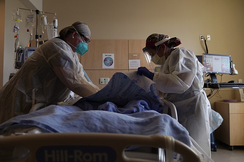 FILE - In this Dec. 22, 2020, file photo, registered nurses Robin Gooding, left, and Johanna Ortiz treat a COVID-19 patient at Providence Holy Cross Medical Center in the Mission Hills section of Los Angeles. Coronavirus deaths in the U.S. hit another one-day high on Tuesday, Jan. 12, 2021, at over 4,300 with the country’s attention focused largely on the fallout from the deadly uprising at the Capitol.