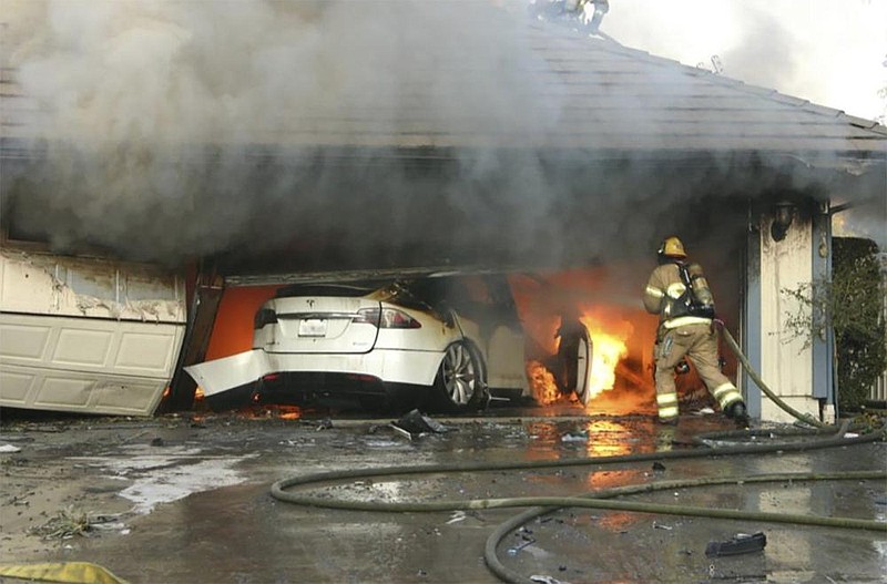 This undated photo provided by the National Transportation Safety Board, firefighters battle a blaze started by an electric vehicle’s high-voltage battery pack in a garage in Orange County, Calif.
(Orange County sheriff’s office/National Transportation Safety Board) story.lead_photo.caption
