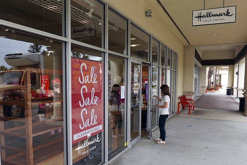 A sale sign is displayed near the entrance of a Hallmark store in Orlando, Fla., on Tuesday, Jan. 12, 2021. Retail sales fell for a third straight month as a surge in virus cases kept people away from stores and restaurants during the holiday shopping season.