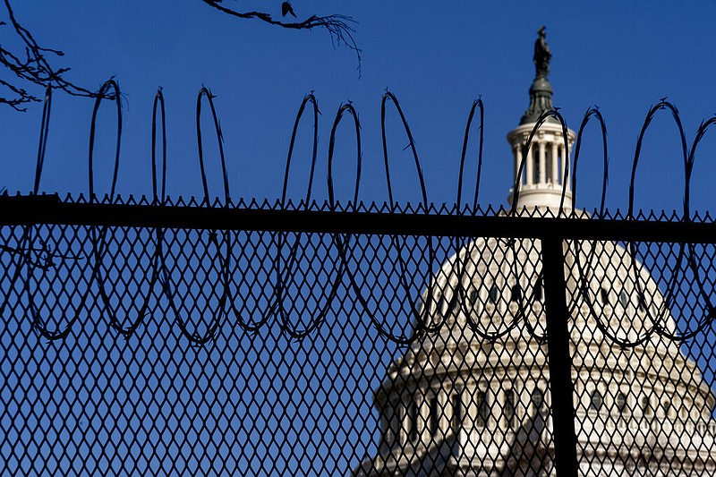 The Dome of the Capitol Building is visible through razor wire installed on top of fencing on Capitol Hill in Washington, Thursday, Jan. 14, 2021.