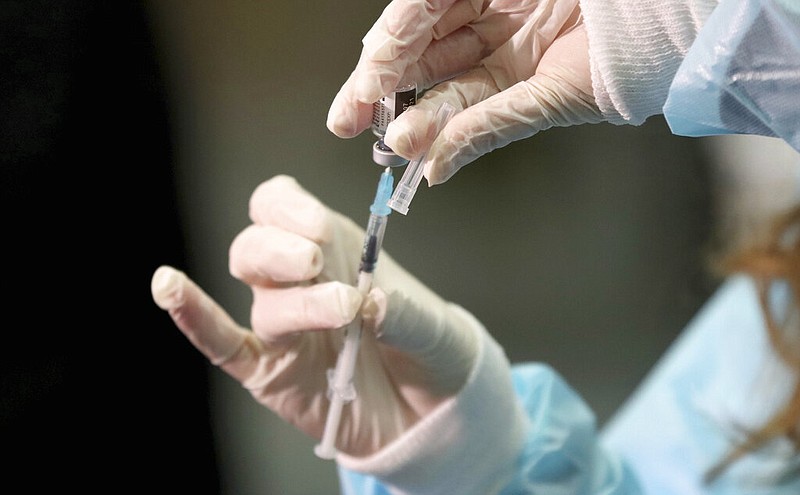 A medical worker holding a Pfizer-BioNTech vaccine and a syringe during mass vaccination starts in Vienna, Austria, Friday, Jan. 15, 2021. Authorities started to vaccinate the most vulnerable people in a coordinated effort.