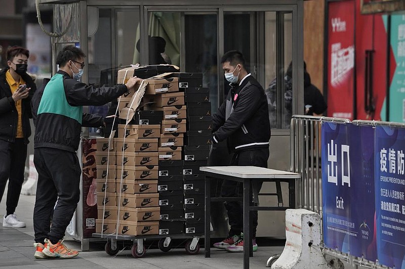 Workers push a cart loaded with shoes made by Nike past a security post Thursday at a shopping mall in Beijing. China’s exports rose in 2020 despite pressure from the coronavirus pandemic and a tariff war with the United States.
(AP/Andy Wong)