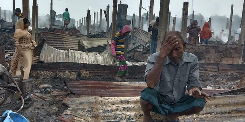 A Rohingya refugee sits Thursday near the charred remains of homes in the Nayapara refugee camp in Bangladesh. More photos at arkansasonline.com/115nayapara/.
(AP/Mohammed Faisal)