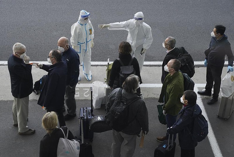 A worker directs members of the World Health Organization team Thursday on their arrival at the airport in Wuhan in central China’s Hubei province. More photos at arkansasonline.com/115wuhan/.
(AP/Ng Han Guan)