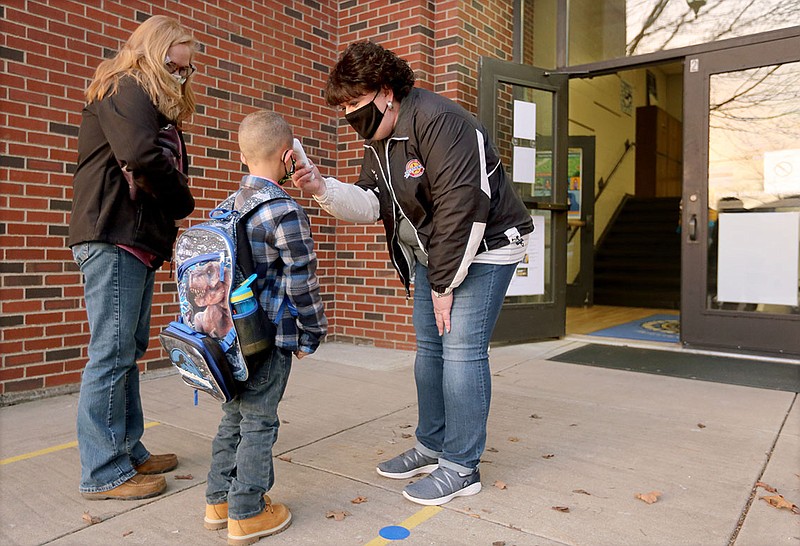 Shannon Ridley (from left) watches as her son Austin, a kindergarten student, has his temperature checked Friday by Ruth Mobley, assistant principal at Washington Elementary School, before he enters the school in Fayetteville. Friday was the first day for Ridley to return to traditional learning after beginning the year virtually through alternative learning. Check out nwaonline.com/210117Daily/ and nwadg.com/photos for a photo gallery.

(NWA Democrat-Gazette/David Gottschalk)