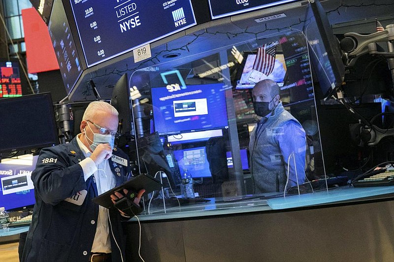 Trader Thomas Ferrigno (left) works Friday on the fl oor of the New York Stock Exchange. Stocks fell Friday after reports showed the pandemic is deepening the hole for the economy.
(AP/New York Stock Exchange/Courtney Crow)