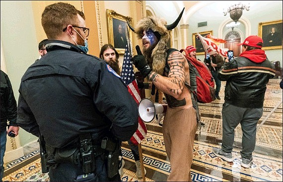 In this Jan. 6 file photo, supporters of President Donald Trump are confronted by U.S. Capitol Police officers outside the Senate Chamber inside the Capitol in Washington. An Arizona man seen in photos and video of the mob wearing a fur hat with horns was also charged Saturday in Wednesday’s chaos. Jacob Anthony Chansley, who also goes by the name Jake Angeli, was taken into custody Jan. 9.