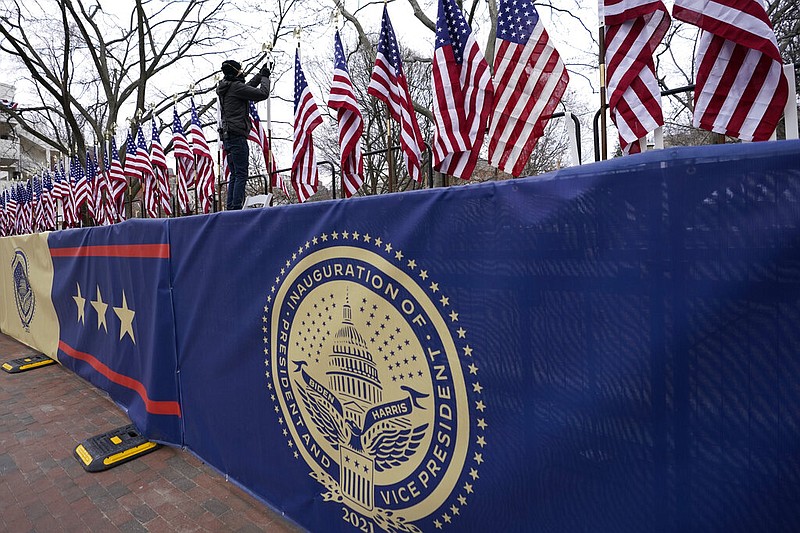 A worker installs flags on Pennsylvania Avenue in front of the White House ahead of President-elect Joe Biden's inauguration ceremony, Tuesday, Jan. 19, 2021, in Washington. (AP Photo/David Phillip)