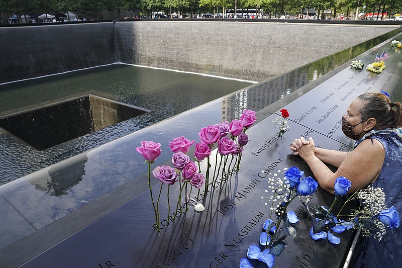 FILE - In this Friday Sept. 11, 2020, file photo, a mourner prays over the etched name of the deceased Emilio Pete Ortiz at the National September 11 Memorial and Museum in New York. Authorities say a U.S. Army soldier has been arrested in Georgia on terrorism charges after he spoke online about plotting to blow up the 9/11 Memorial in New York City and attack U.S. soldiers in the Middle East. (AP Photo/John Minchillo, File)