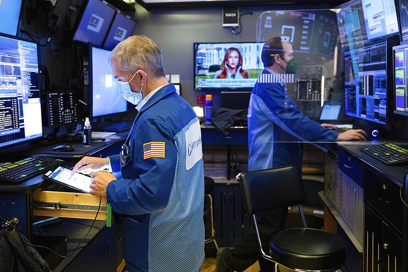 In this photo provided by the New York Stock Exchange, trader Timothy Nick, left, and a colleague work in a booth on the trading floor, Tuesday, Jan. 19. 2021.