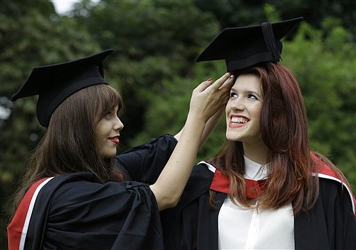 Carrie Harwood (left) adjusts the mortarboard for her friend, Lucy Nicholls, ahead of Nicholls' graduation in this July 2012 file photo.