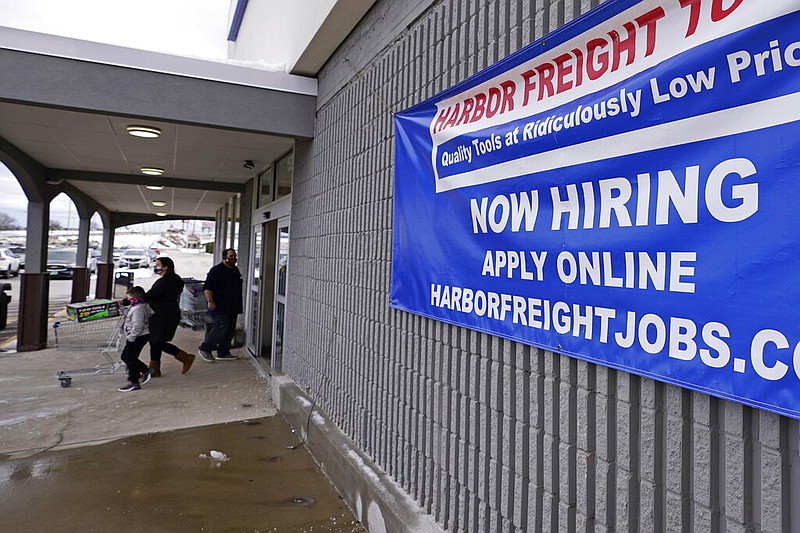 FILE - In this Dec. 10, 2020, file photo, a "Now Hiring" sign hangs on the front wall of a Harbor Freight Tools store in Manchester, N.H.
