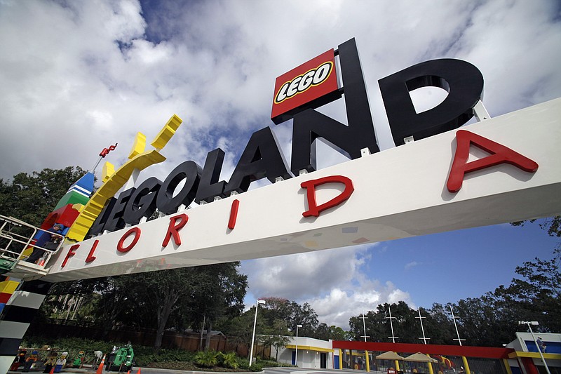 In this 2011 file photo, a worker puts finishing touches on the entrance sign at Legoland Florida in Winter Haven, Fla. The Legoland theme park in Florida is installing tents over the entirety of its MiniLand USA … tiny versions of American cities and landmarks. (AP Photo/John Raoux)