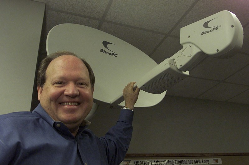 Terry Fleming, then president of what was called Perfect 10 Satellite Distributors in North Little Rock, poses with one of the dishes distributed by his company in this March 23, 2001, file photo.