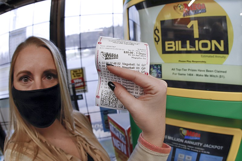 A patron, who did not want to give her name, shows the ticket she had just purchased for the Mega Millions lottery drawing at the lottery ticket vending kiosk in a Smoker Friendly store, Friday, Jan. 22, 2021, in Cranberry Township, Pa. The jackpot for the Mega Millions lottery game has grown to $1 billion ahead of Friday night's drawing after more than four months without a winner. (AP Photo/Keith Srakocic)