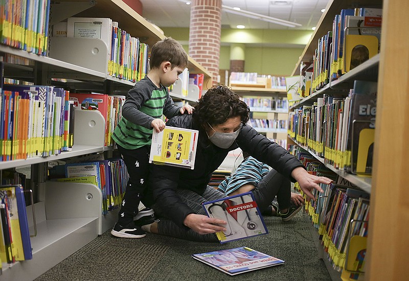 Danielle Sanders of Bentonville (center), picks out books with sons  Tyler Sanders, 3, (left) and Henry Sanders, 4, (rear), Thursday, January 21, 2021 at the Bentonville Library in Bentonville. Bentonville residents could be asked to approve $266 million in bonds for street and park improvements as well as other capital projects in the city. Library plans call for 6,400-square-foot addition and renovations to 10,000 square feet of the interior of the building. The addition would include a children's expansion, which would include a larger story time area and larger craft space. There would also be a teen space and maker space. Check out nwaonline.com/210119Daily/ for today's photo gallery. 
(NWA Democrat-Gazette/Charlie Kaijo)