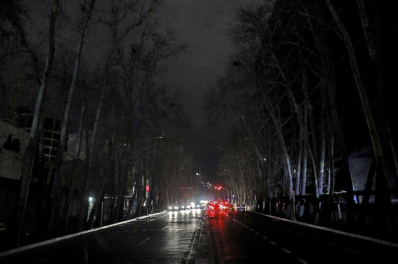 Vehicles travel on an unlit street during a blackout this week in Tehran as Iran endures a series of power failures.
(AP/Ebrahim Noroozi)