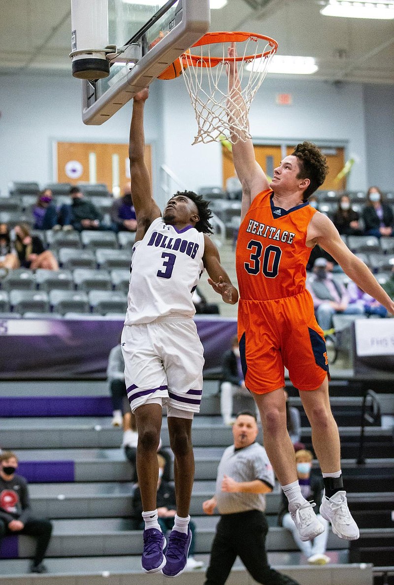 Fayetteville’s Landon Glasper (left) goes for a layup as Rogers Heritage’s Ian McChristian defends during Friday night’s 6A-West Conference game at Bulldog Arena in Fayetteville. Glasper scored 26 points in the Bulldogs’ 61-48 victory over the War Eagles.
(Special to the NWA Democrat-Gazette/David Beach)