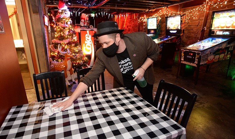 Bo Counts wipes down tables with disinfectant at his Fayetteville bar, Pinpoint, in this Jan. 7, 2021, file photo. Bar owners in Fayetteville filed a lawsuit to lift an 11 p.m. curfew on serving alcohol.