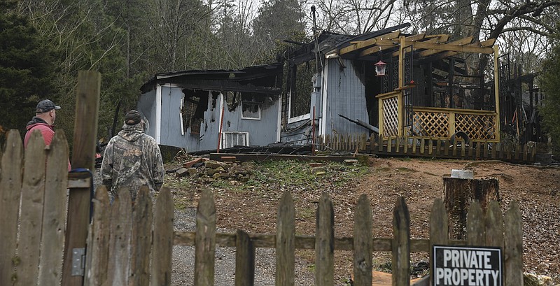 Family members survey the damage caused by a fire that reportedly killed a Garland County man and two of his three dogs early Sunday. (Grace Brown/Hot Springs Sentinel-Record)