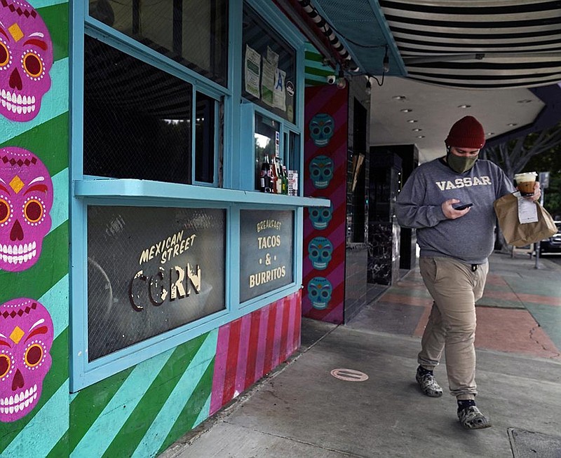 A person picks up food Monday at a restaurant in Los Angeles. Cali- fornia has lifted regional stay-at-home orders in response to a drop in covid-19 cases and hospitalizations. More photos at arkansa- sonline.com/126psaki/.
(AP/Damian Dovarganes)