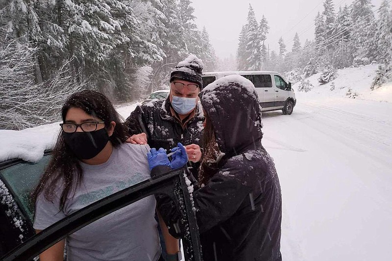 Josephine County Sheriff’s Deputy Nicole Letona receives a covid-19 vaccination Thursday from Dr. David Candelaria and Leah Swanson, Josephine County emergency preparedness coordinator, near Hayes Hill, Ore. The health workers got stuck in a snowstorm as they returned from a covid-19 vaccination event and went car to car injecting stranded drivers before the leftover unfrozen doses expired.
(AP/Josephine County Public Health)