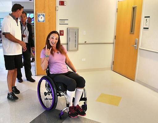 Amy Van Dyken-Rouen, a six-time Olympic gold medalist in swimming, gestures as she leaves Craig Hospital in Englewood, Colo., with her husband, Tom Rouen (left), in this Aug. 14, 2014, file photo. Van Dyken-Rouen was left paralyzed just below the waist in an all-terrain vehicle crash on June 6, 2014, but has kept an upbeat, positive presence on social media. As of 2021, her Instagram features photos of her smiling, working out and spending time with her family and her dog.