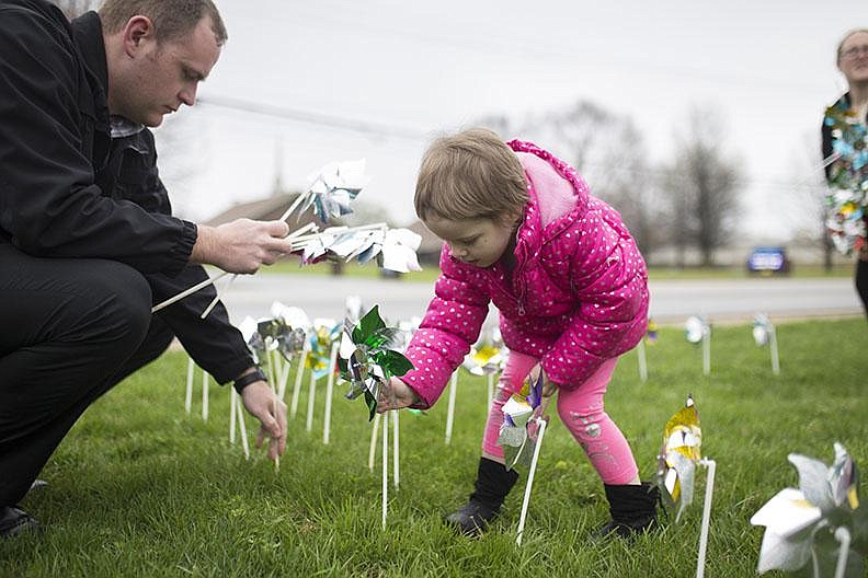 Elizabeth Crouch and Bentonville Police Department detective Adam Corbett place pinwheels out- side the police station during an April 2018 Cherishing Children rally held to recognize child-abuse investigators and promote prevention of child maltreatment. Each pinwheel represents a confirmed case of child abuse and signifies a child’s innocence.
(NWA Democrat-Gazette/Charlie Kaijo)