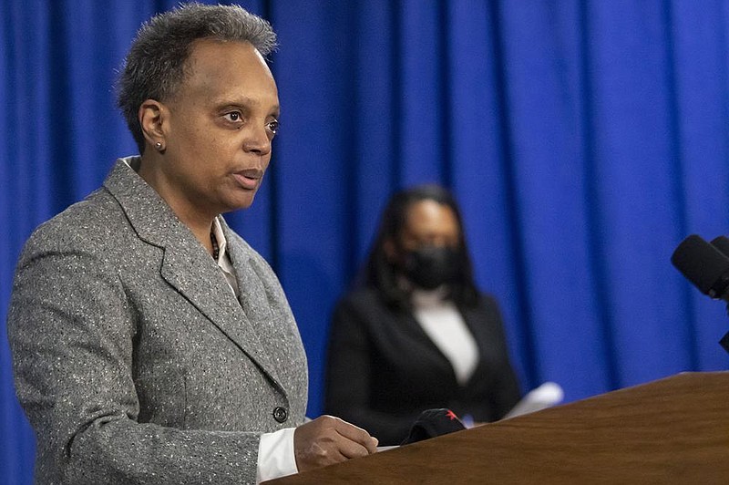 Mayor Lori Lightfoot, at podium, and Chicago Public Schools CEO Janice Jackson, background, announce Sunday, Feb. 7, 2021, at City Hall that a tentative agreement has been reached with the Chicago Teachers Union to reopen schools, in Chicago. The proposed deal is subject to an approval vote by CTU's House of Delegates. (Brian Cassella/Chicago Tribune via AP)