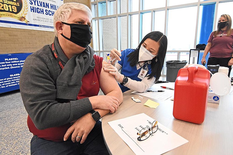 Angela Hughes, a nurse for the Pulaski County Special School District, gives Aaron Bussard, a school speech therapist, his first dose of the coronavirus vaccine Wednesday, Feb. 10, 2021 at Sylvan Hills High School in Sherwood.
(Arkansas Democrat-Gazette/Staci Vandagriff)