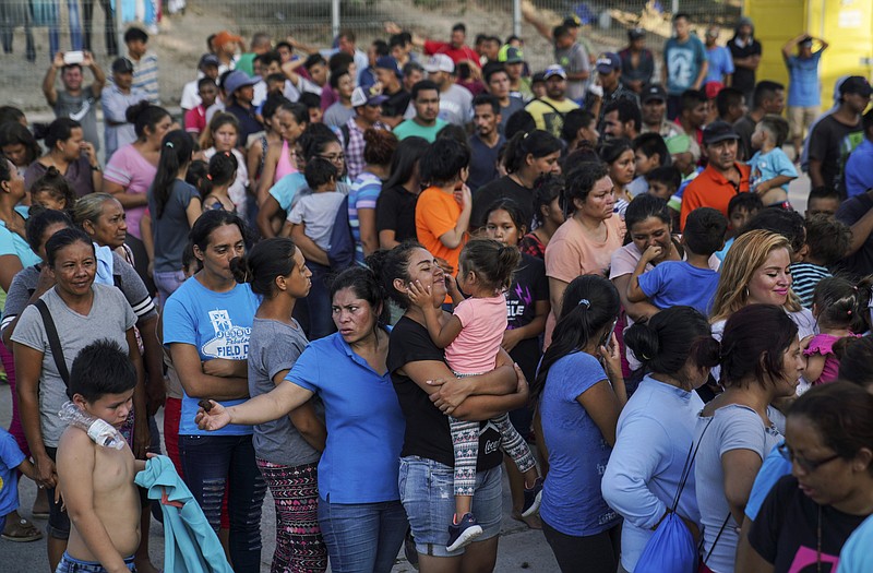 FILE - In this Aug. 30, 2019, file photo, migrants, many of whom were returned to Mexico under the Trump administration’s “Remain in Mexico” policy, wait in line to get a meal in an encampment near the Gateway International Bridge in Matamoros, Mexio. The Biden administration on Friday, Feb. 12, 2021, announced plans for tens of thousands of asylum-seekers waiting in Mexico for their next immigration court hearings to be released in the United States while their cases proceed. (AP Photo/Veronica G. Cardenas, File)