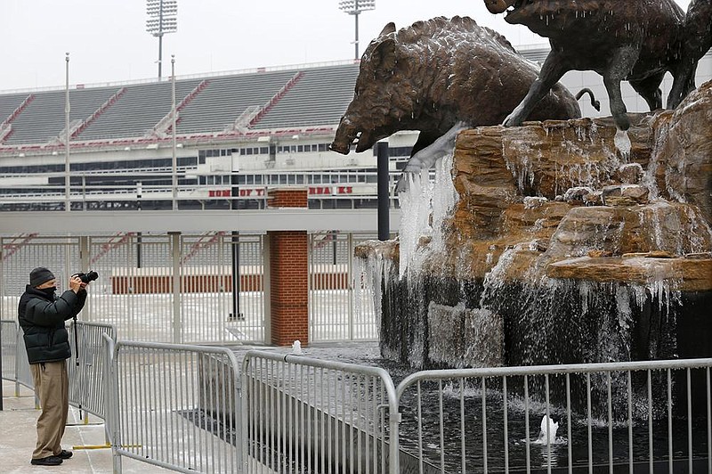 Jack Demaree photographs the ice Thursday formed on the trotters of the Wild Band of Razorbacks monument on the northeast corner of Reynolds Razorback Stadium on the campus of the University of Arkansas in Fayetteville. The National Weather forecast for today in the Northwest Arkansas area is for mostly cloudy and a high near 29 degrees. Go to nwaonline.com/210212Daily/ and nwadg.com/photos for a photo gallery.
(NWA Democrat-Gazette/David Gottschalk)