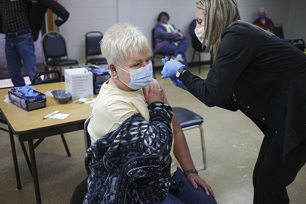Registered nurse Shanna Workman (right) administers a covid-19 vaccine Friday to Mary Tompkins
of Bella Vista at Riordan Hall.
(NWA Democrat-Gazette/Charlie Kaijo)