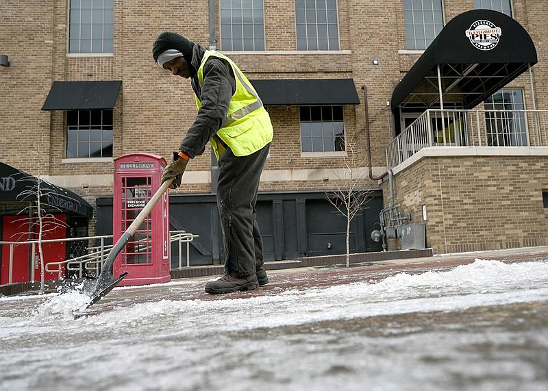 Roosevelt Duncan, a maintenance worker with the Little Rock Parks and Recreation Department, shovels ice Friday in the River Market District.
(Arkansas Democrat-Gazette/Stephen Swofford)