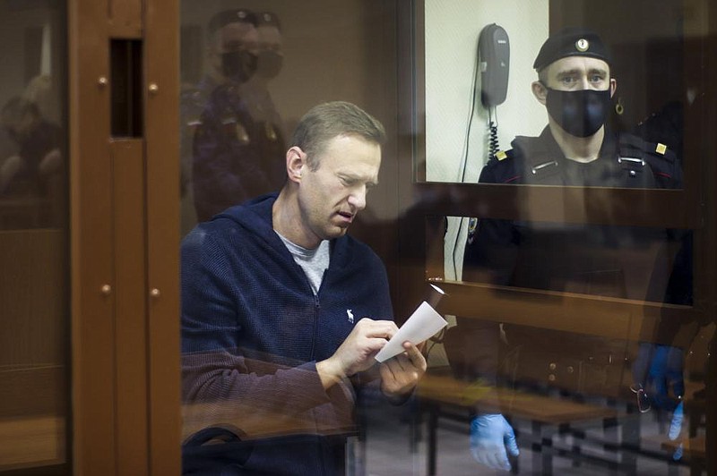 Russian opposition leader Alexei Navalny, facing defamation charges, writes a note Friday during a hearing in the Babuskinsky District Court in Moscow. Navalny is accused of slandering a World War II veteran.
(AP/Babuskinsky District Court Press Service)
