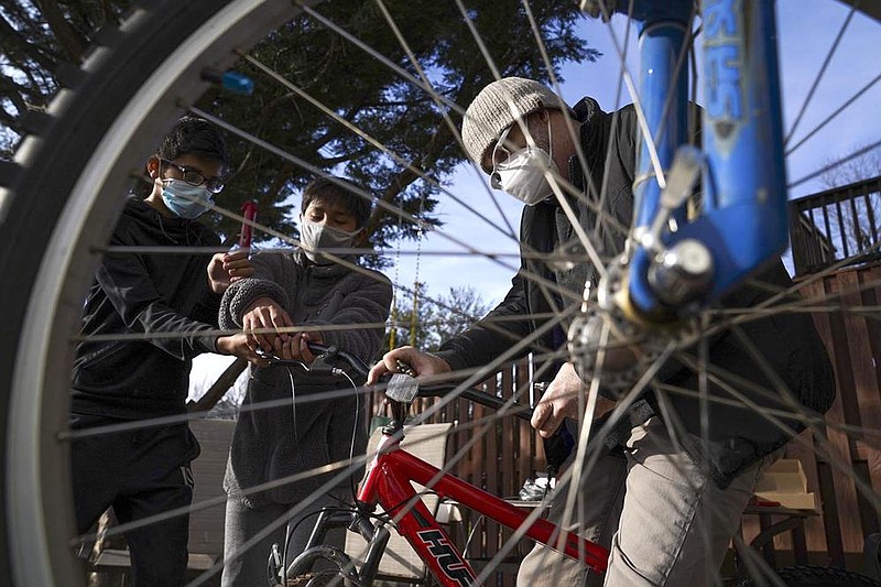 Umer Mahmood (left) and Santi Palomino (center) help Robbie Pruitt repair their bikes in Ashburn, Va.
(The Washington Post/Jahi Chikwendiu)