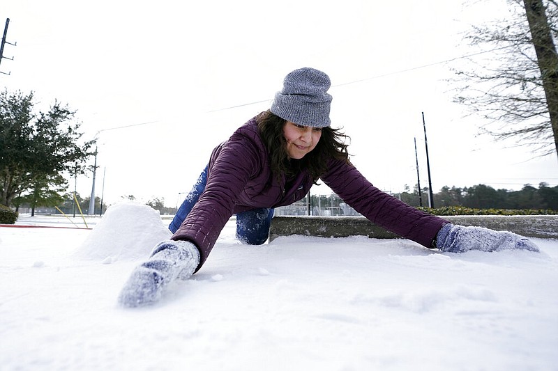 Cristina Lucero gathers snow while trying to build a snowman Monday, Feb. 15, 2021, in Houston.