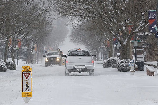 Snow falls Monday, Feb. 15, 2021, as light traffic moves down Dickson Street in Fayetteville. The National Weather Service is forecasting several inches of snow throughout the state through Wednesday and Thursday.
