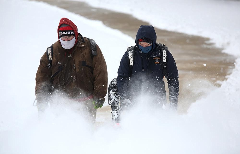 Lee Anderson (left) and Ben Hall of the University of Arkansas facilities and grounds department use leaf blowers Wednesday to remove snow from the northwest corner of Donald W. Reynolds Razorback Stadium on the Fayetteville campus.
(NWA Democrat-Gazette/David Gottschalk)