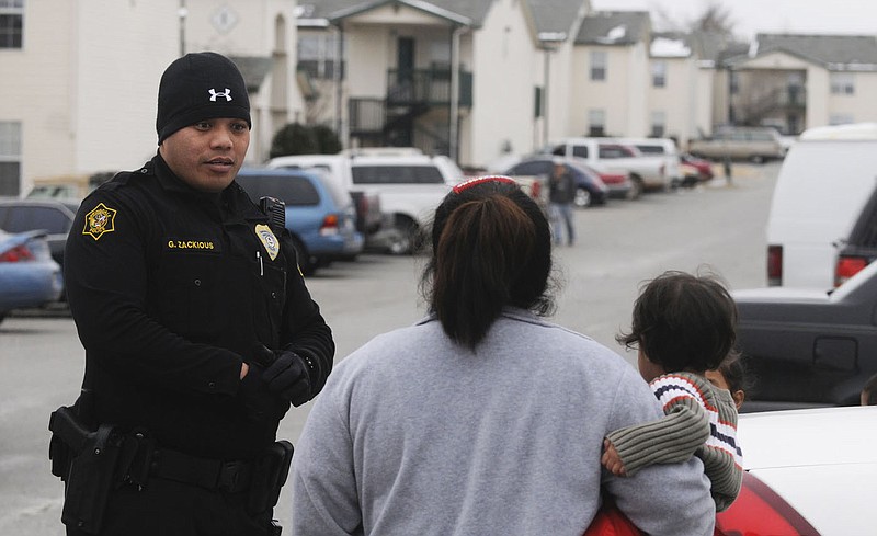 Springdale Police officer Gomez Zackious speaks Marshallese to a woman during an iinvestigation in 2010 in Springdale. Marshallese residents can serve in local law enforcement agencies if the state Department of Public Safety changes its rules, the agency said Wednesday.
(File Photo/NWA Democrat-Gazette)