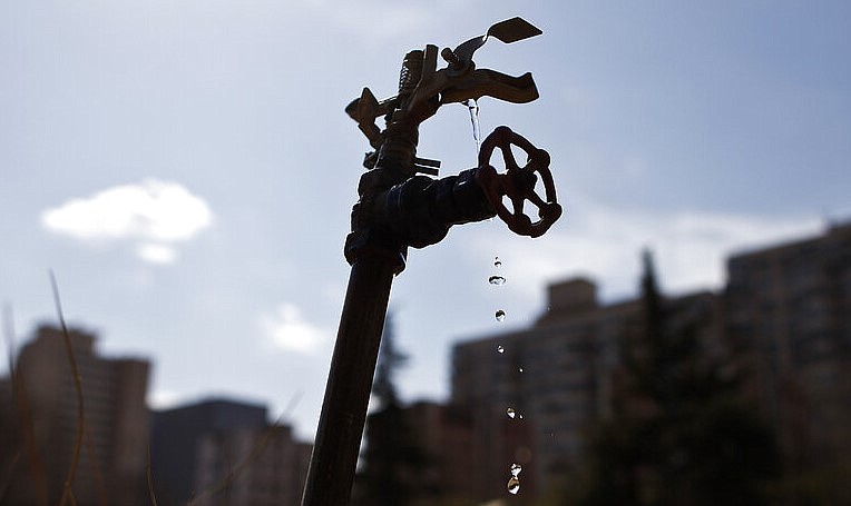 Water is seen dripping from a water sprinkler against residential apartment buildings in this March 24, 2011, file photo.