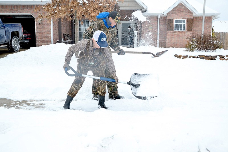 Gavin Carter and Landon King, both 12, shovel snow off a sidewalk in Summit Meadows in Pea Ridge where they've been clearing walks and driveways for neighbors during the recent snow storms.
