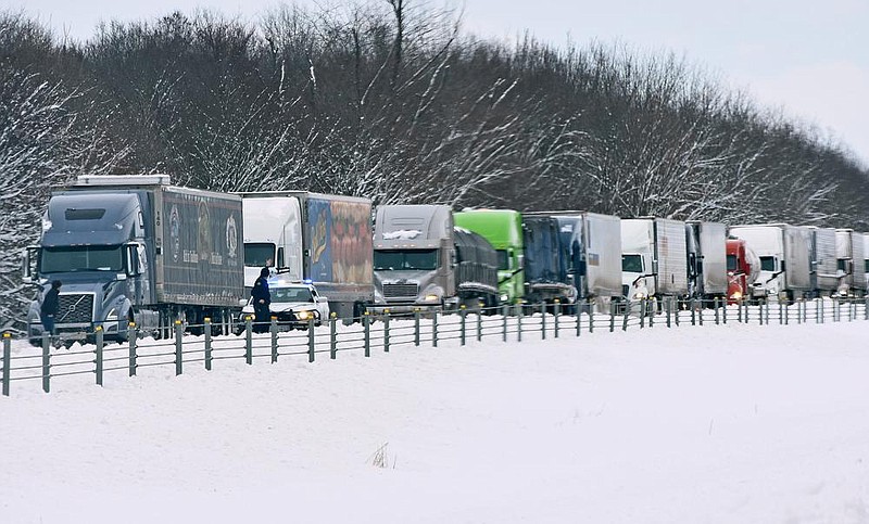 An Arkansas State trooper’s vehicle Thursday blocks the Galloway exit on Interstate 40 as trucks stack up along the highway. Officers blocked both exits to prevent additional trucks and passenger cars from getting stuck in the snow around truck and travel centers near those exits. More photos at arkansasonline.com/219snow/.
(Arkansas Democrat-Gazette/Staci Vandagriff)